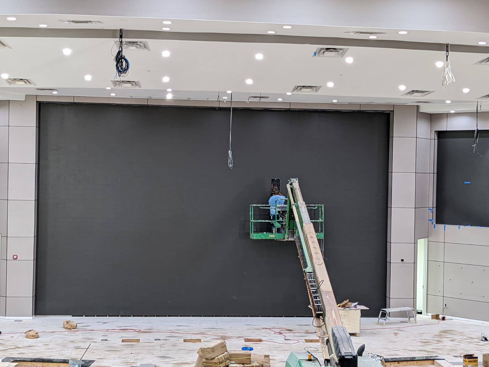 Technician on a boom lift at a large blank LED wall backing before panels are installed