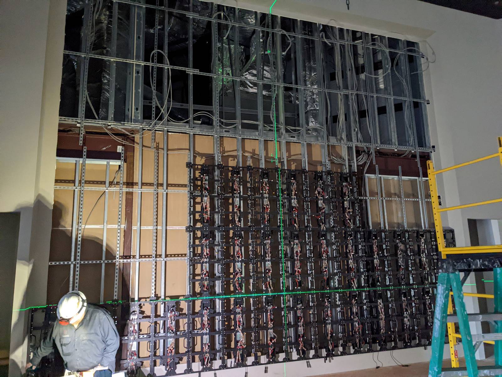 LED panel mounting frames being installed with green laser level lines