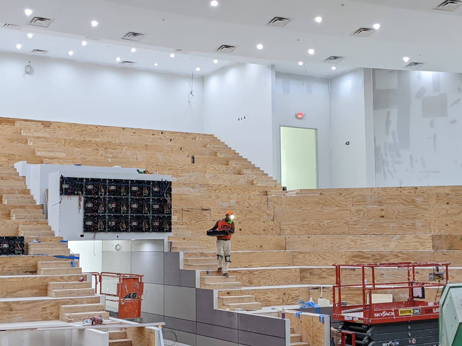 Tiered auditorium under construction with LED panel frames on the wall