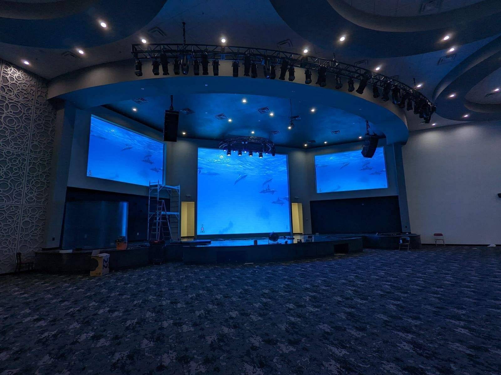 Darkened worship sanctuary with three LED video walls displaying underwater scenes
